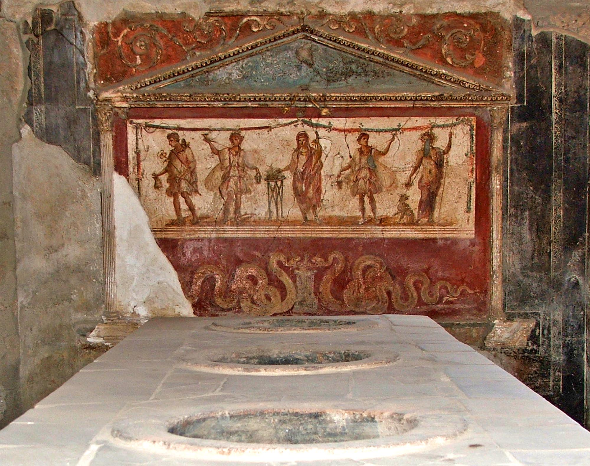A fresco from the thermopolium of Lucius Vetutius Placidus in the city of Pompeii, depicting the spirit (genius) of the house central, flanked by Lares and Penates with Mercury on far left, Bacchus far right