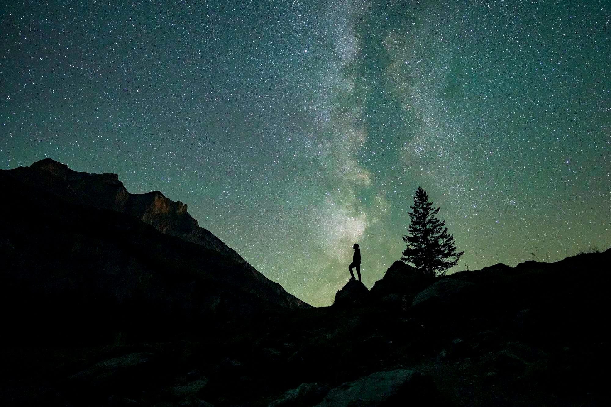 A human, aligned with the Milky Way, looks at the stars from Oeschinensee (Switzerland) during Perseids in search of shooting stars.
