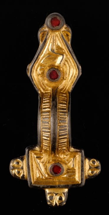 This close-up depicts a bow brooch, a decorative fastening used to secure cloaks, tunics, or other fine garments