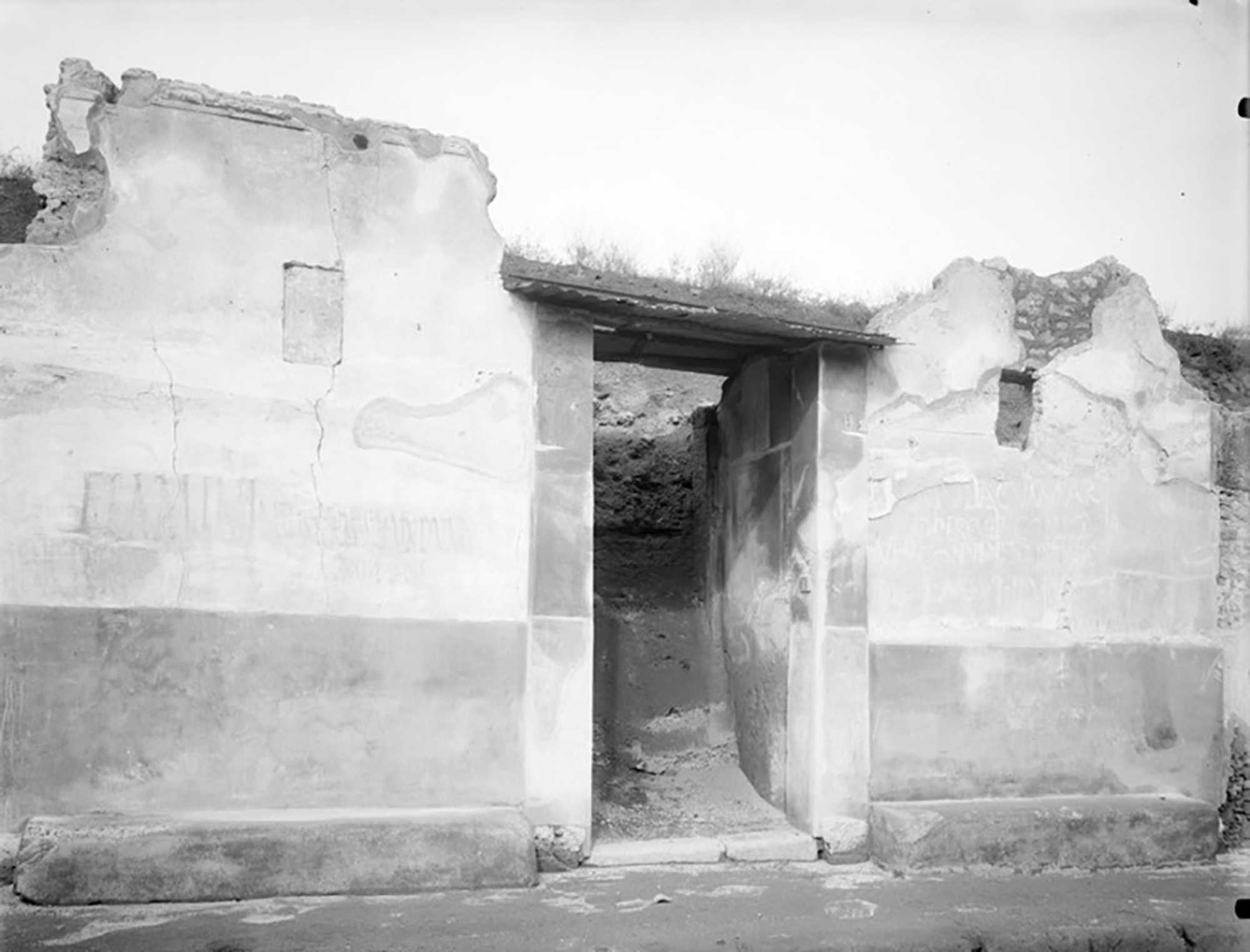 The inscription was on the façade of III.7.1 at Pompeii, on the right side of the entrance, beneath a later plaster layer. It advertised used roofing material for sale and reads approximately: “Roof tiles, cover tiles, drains for sale; come to the usual place to make a deal.”