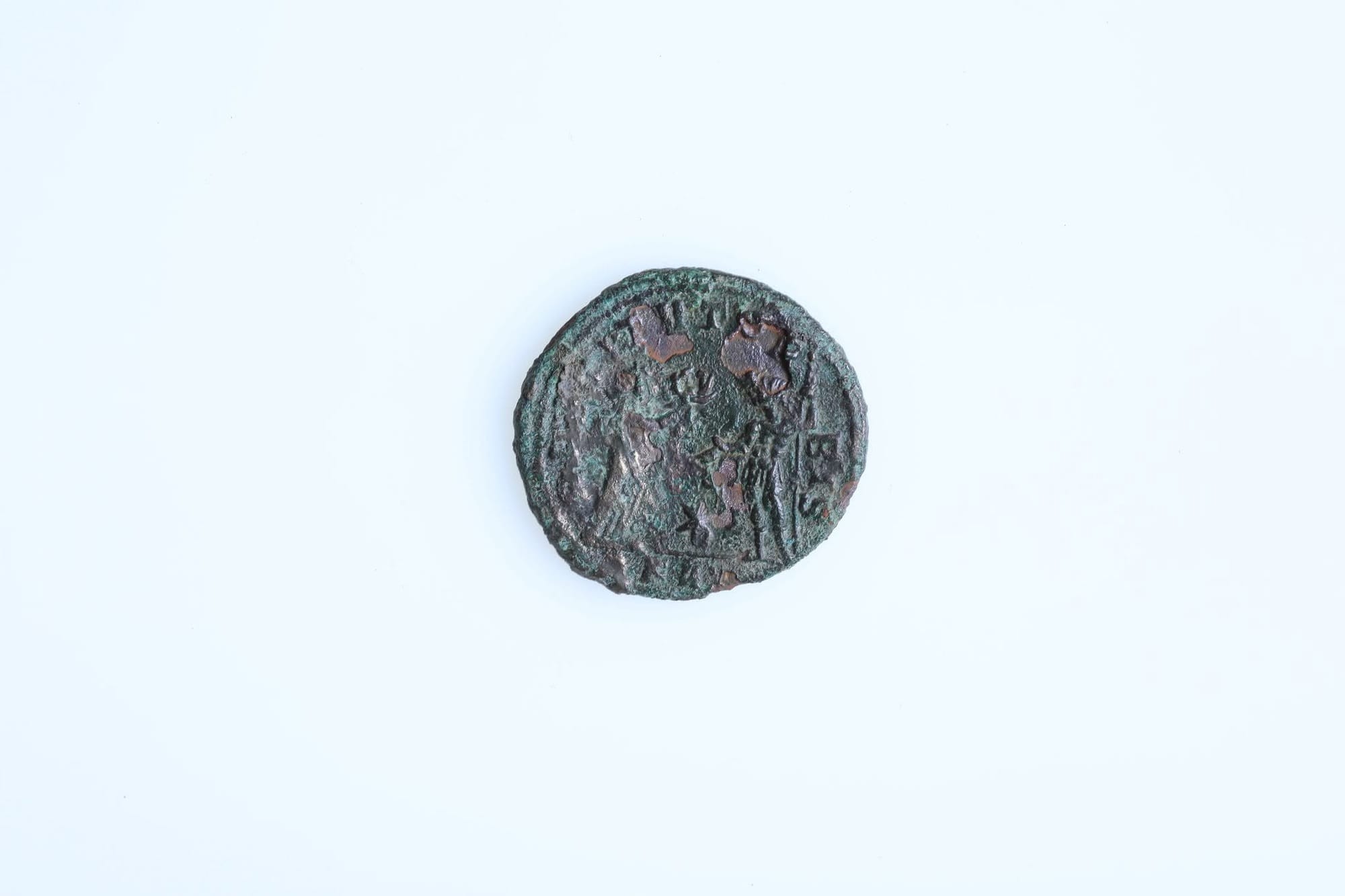 Reverse side of the Aurelian coin from the child’s grave, photographed against a pale background.