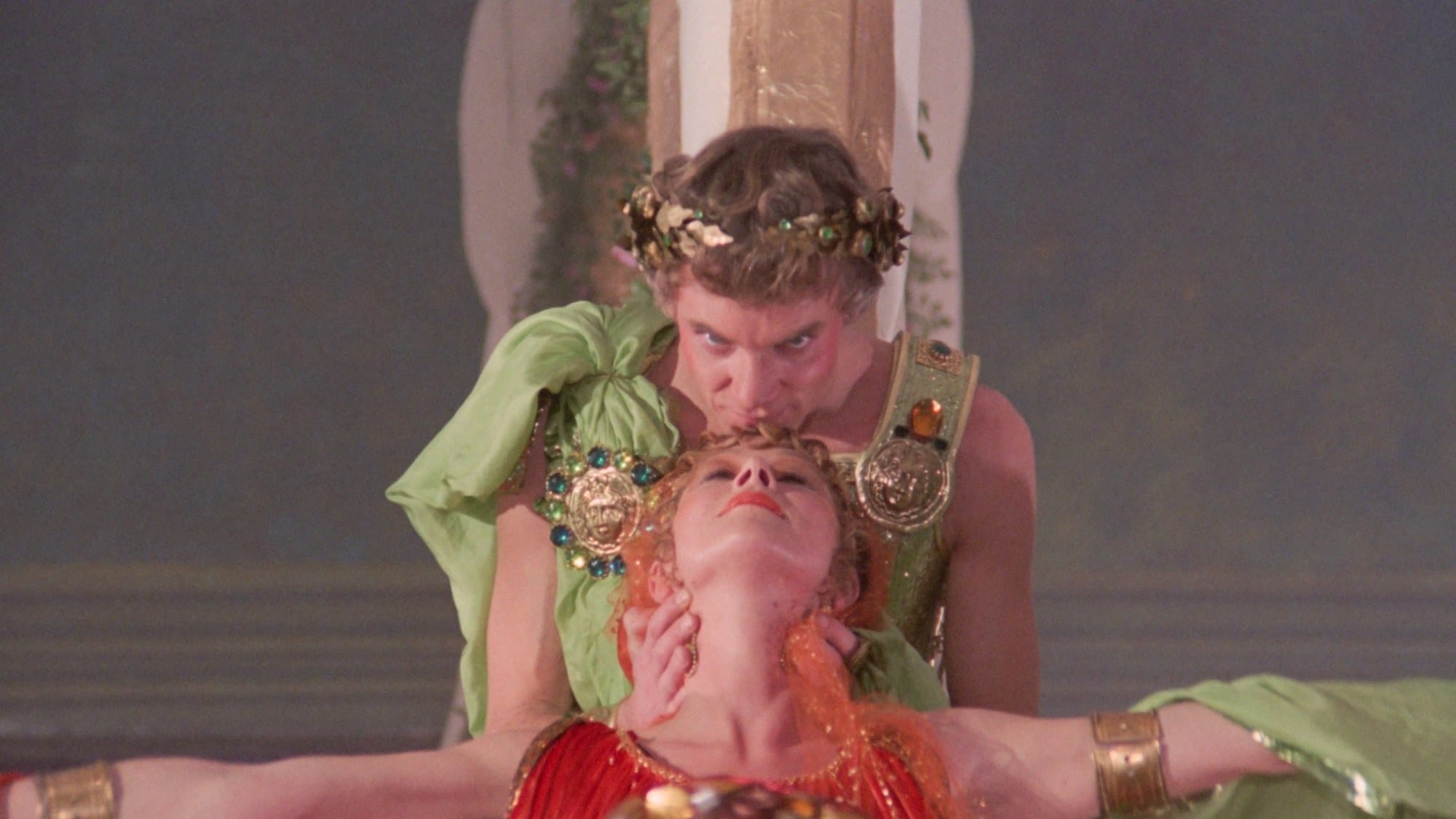 Malcolm McDowell as Caligula seated in elaborate green and gold imperial costume in The Ultimate Cut.