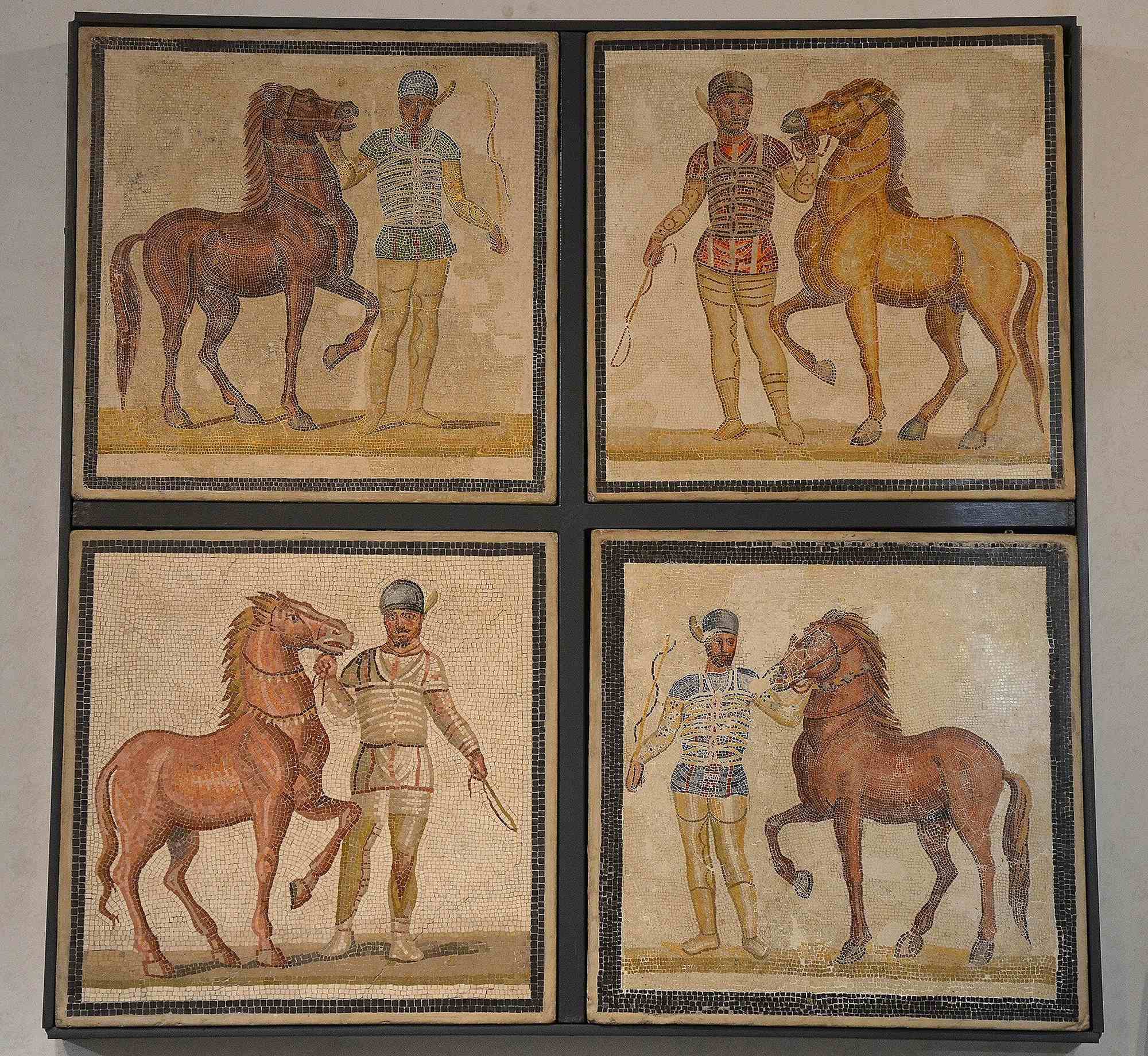 Four mosaic panels depict charioteers and horses, with drivers wearing red, white, blue and green.