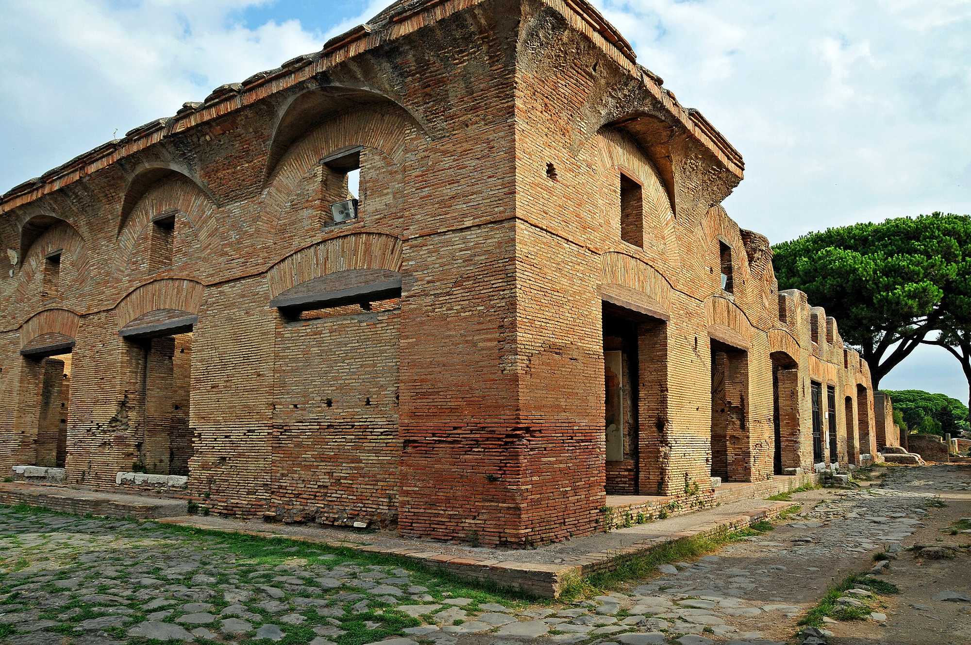 A multi-storey brick apartment building with street-level doorways and upper windows at Ostia Antica.