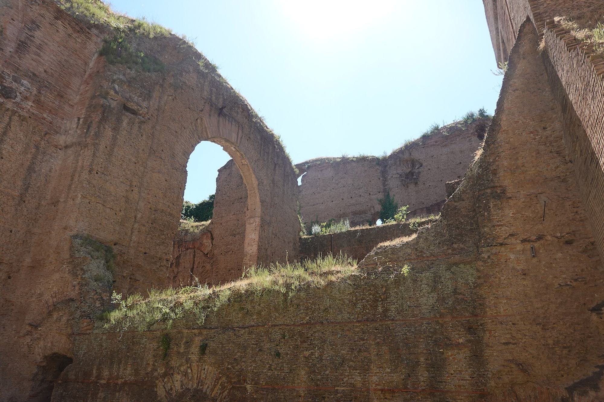 Tall brick arches and walls survive amid green lawns at the Baths of Caracalla in Rome.