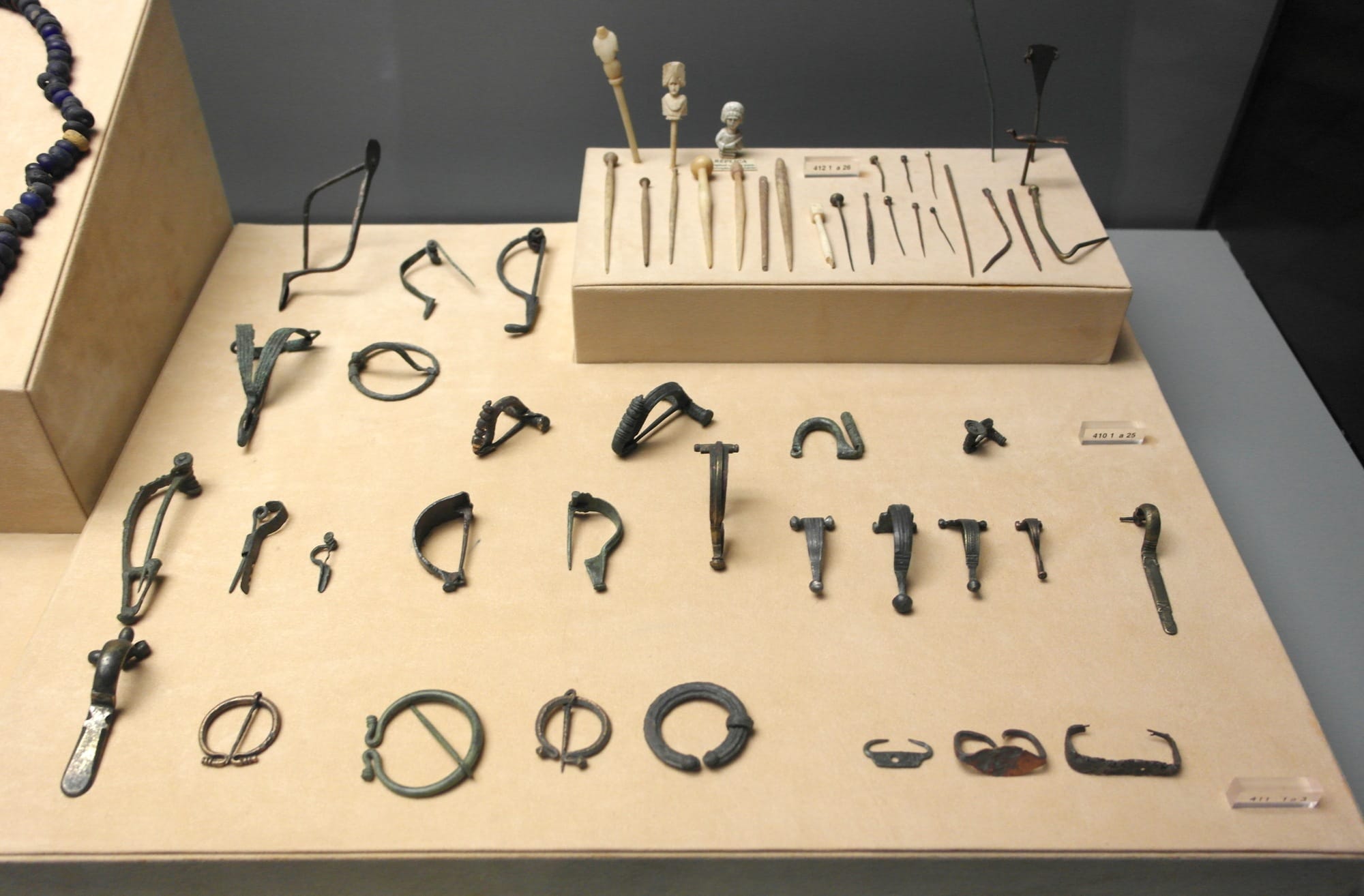 Rows of bronze brooches of different shapes in a display case at the museum of Conímbriga, Portugal.