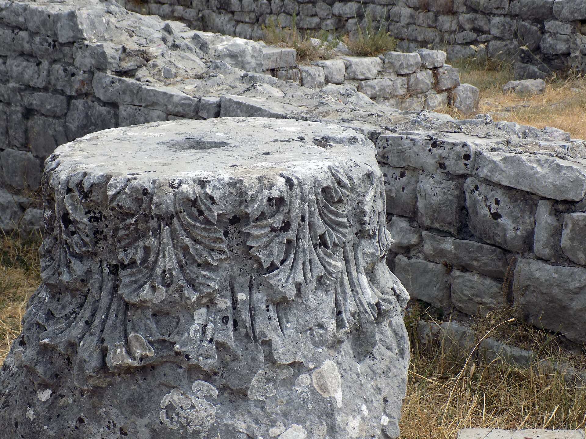 Carved stone capital with leaf decoration among masonry at the Roman ruins of Doclea.
