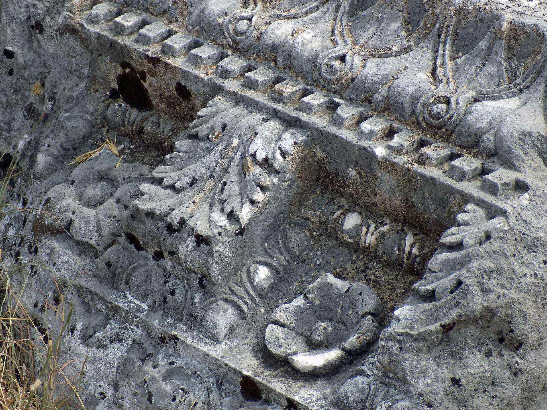 Close-up of carved leaves, scrolls and geometric moulding on a stone fragment at Doclea.