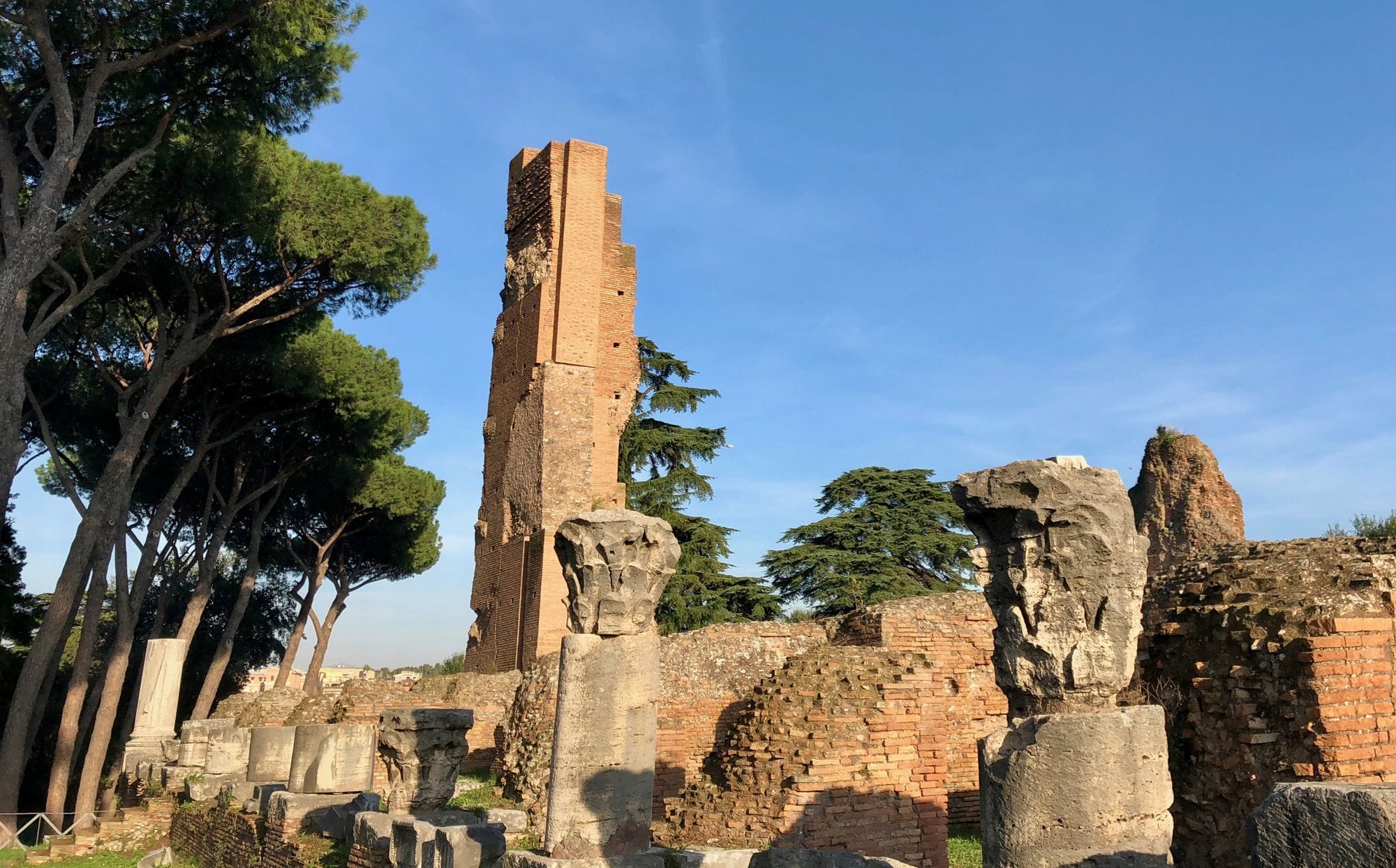 Surviving brick walls and column fragments of the Domus Flavia on the Palatine Hill in Rome, beneath a clear blue sky.