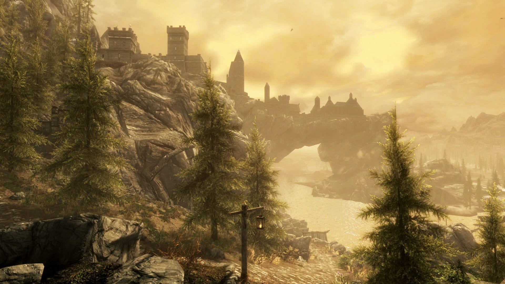 The fortified city of Solitude rises above a river and pine-covered cliffs in The Elder Scrolls V: Skyrim Special Edition.