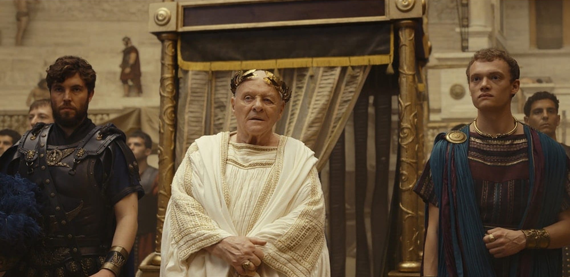 Titus, Vespasian and Domitian stand together in an imperial room in Those About to Die.