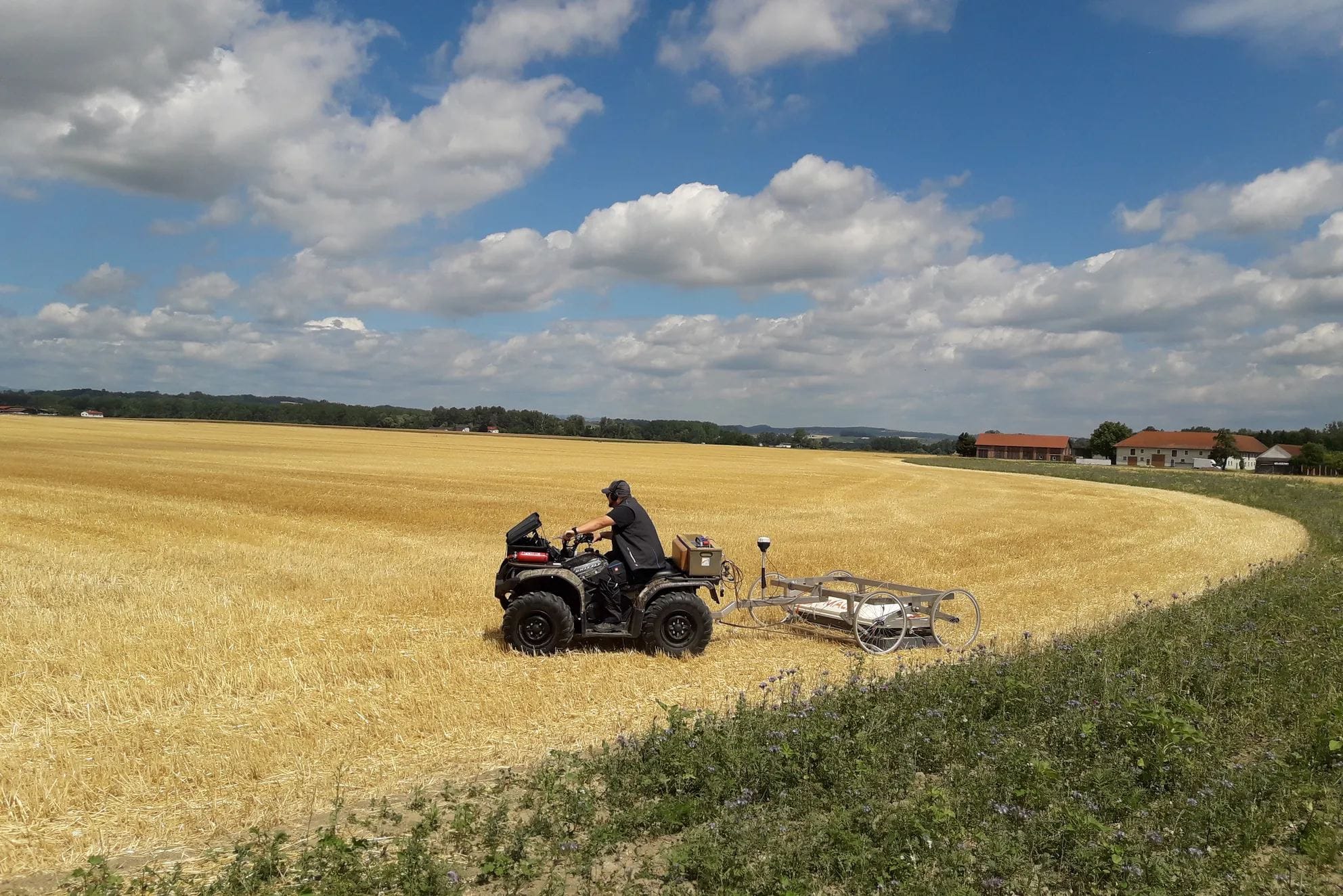 Quad bike towing geophysical survey equipment across a field at Stein