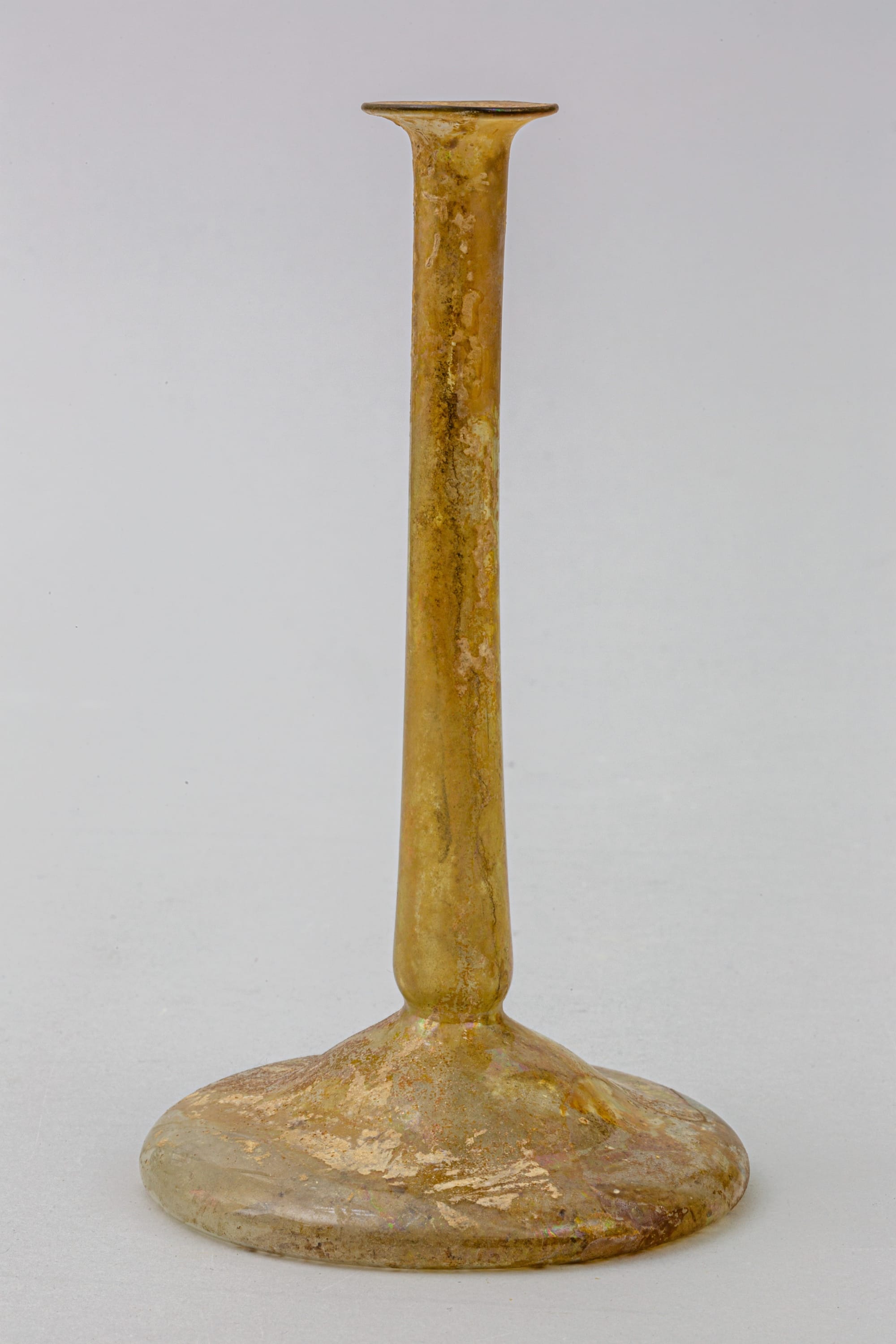 Roman glass candlestick perfume bottle with a tall narrow neck and broad flattened base, 2nd–3rd century CE.