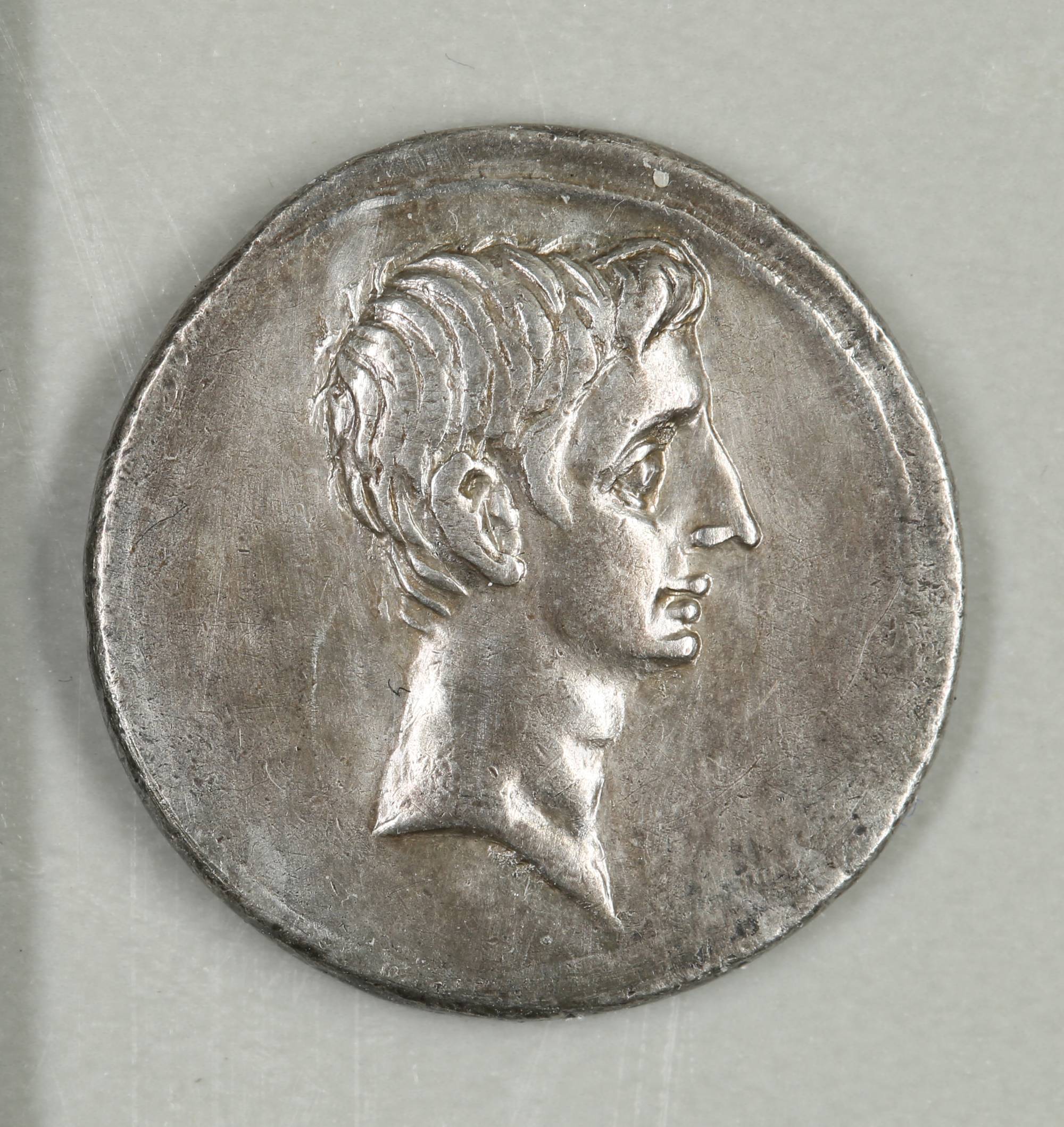 Close-up of Octavian’s right-facing portrait on a worn silver Roman denarius dated 29–27 BC.
