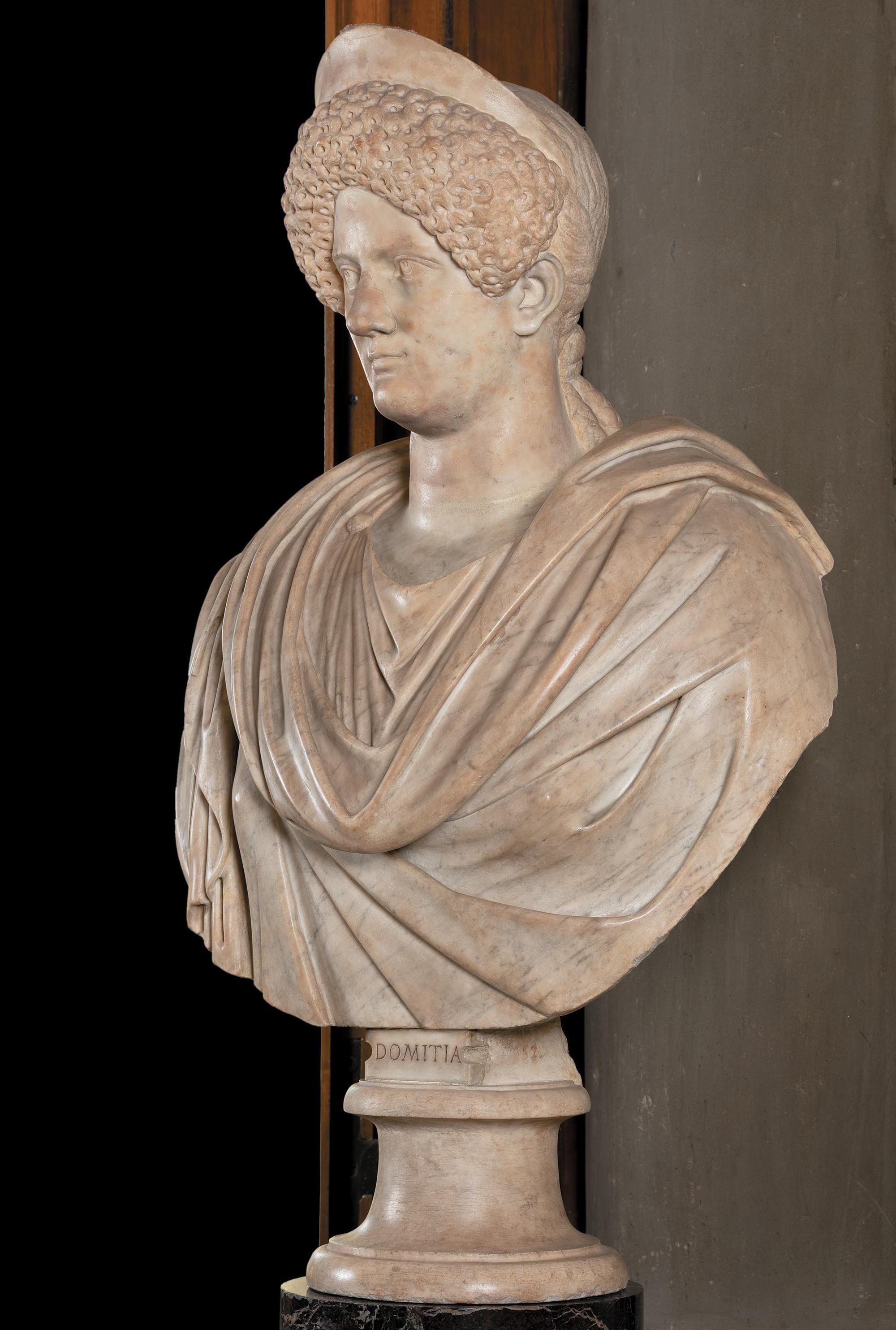 Marble portrait of Domitia Longina with a high curled hairstyle and diadem, mounted on a draped bust.