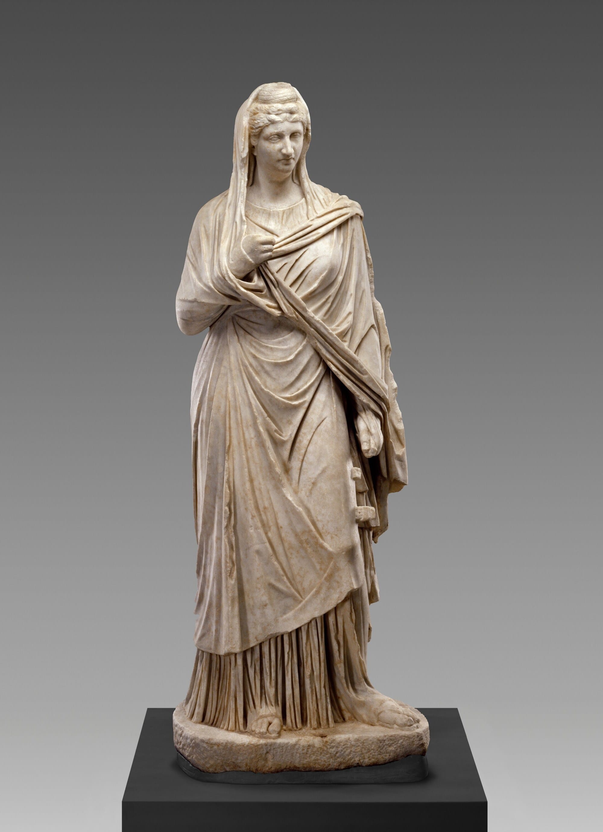 Full-length Roman marble statue of Faustina the Elder, wearing a long draped garment and a mantle over her hair.