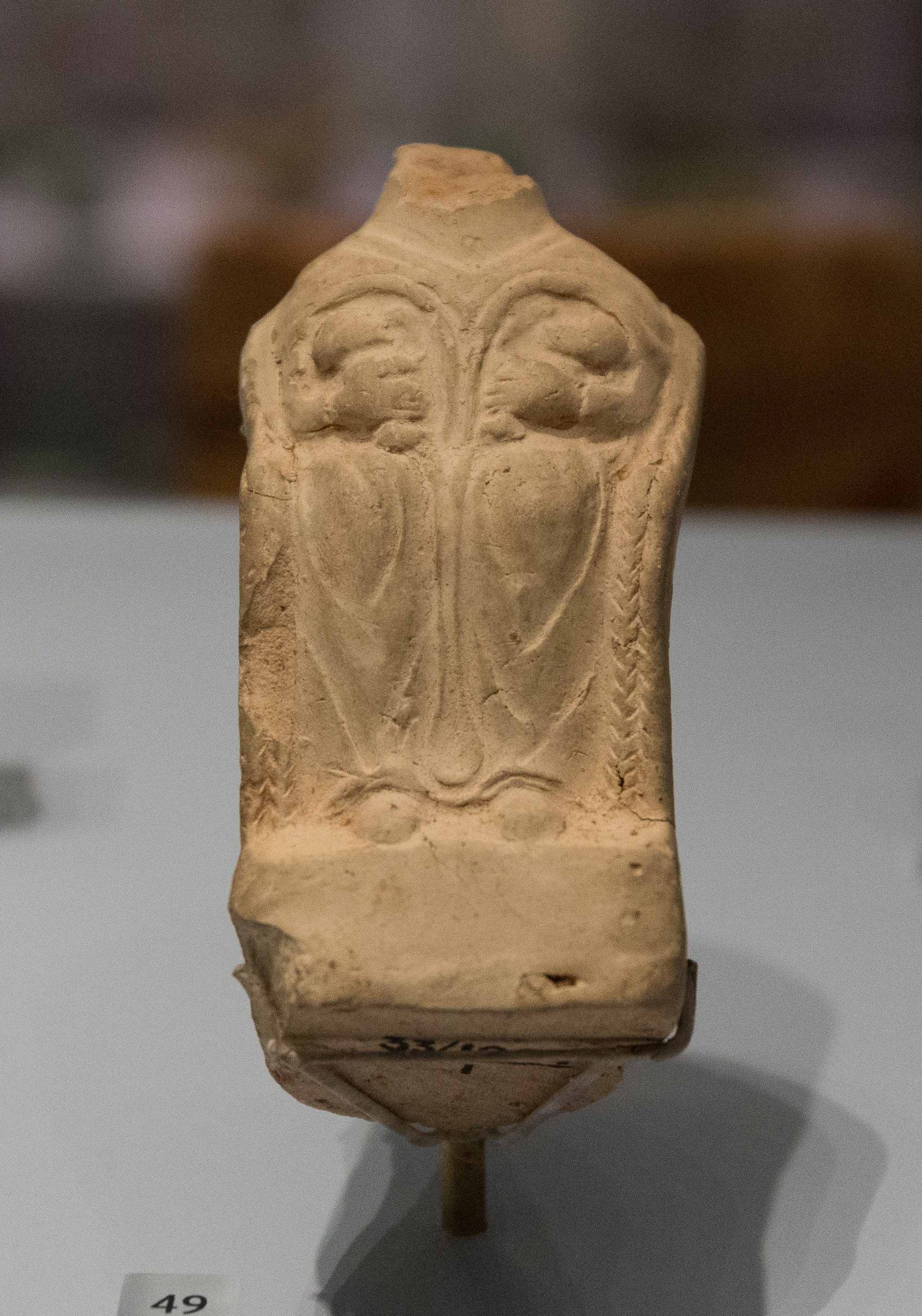 Headless ceramic Roman Dea Nutrix figurine seated in a chair and nursing two babies.