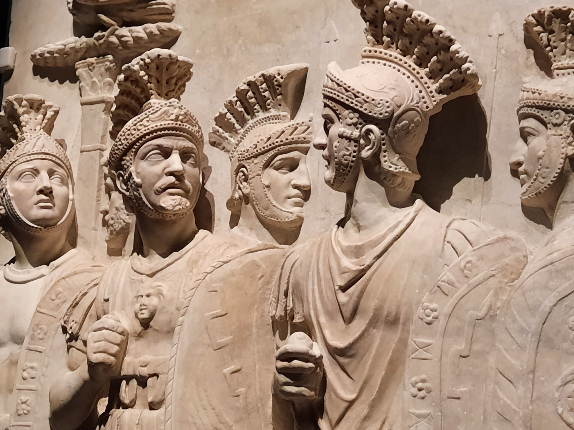 Roman soldiers in decorated helmets and armour on the marble Praetorians Relief, with restored heads, in the Louvre collection.
