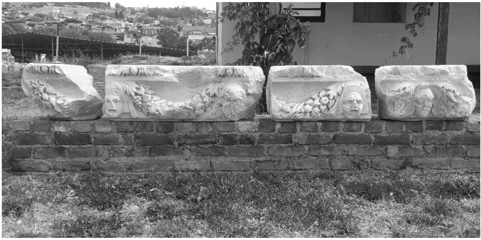 Carved theatrical masks and garlands on four surviving stone frieze blocks from Smyrna’s theater.
