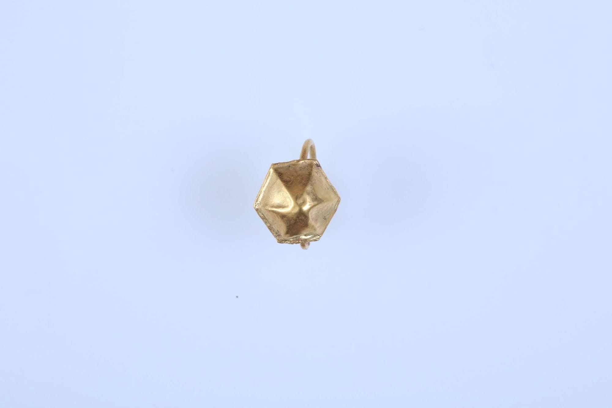 Gold earring with a faceted ornament and loop, recovered beside the child’s right ear.