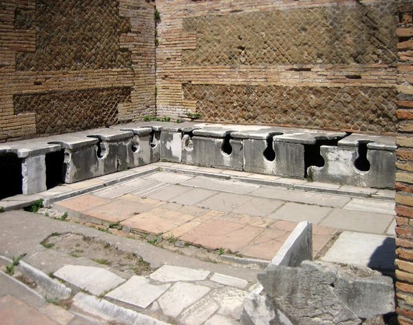 Stone seats and drainage channels in the Roman public latrine opposite the Forum Baths at Ostia Antica.