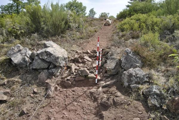Excavated stonework and measuring staff at the Roman camp near La Peña del Castro in León, Spain.