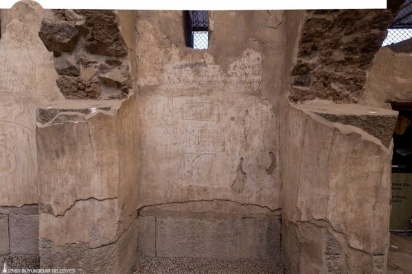 Ancient drawings and lettering on surviving plaster between stone supports in Smyrna’s Roman agora.