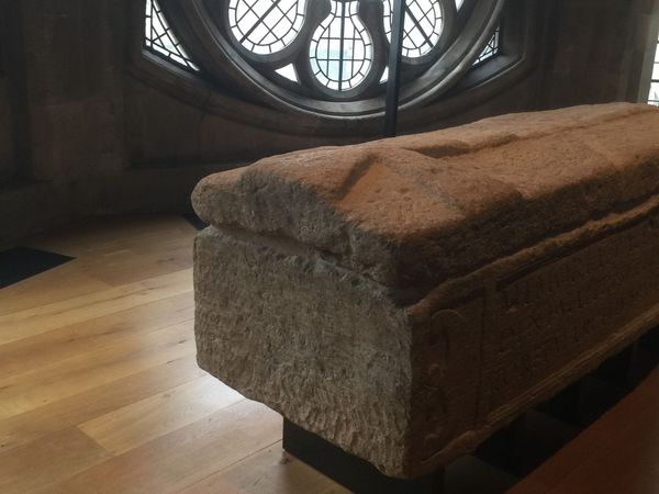 Roman limestone sarcophagus of Valerius Amandinus beneath a window at Westminster Abbey, with a medieval cross carved on its lid.