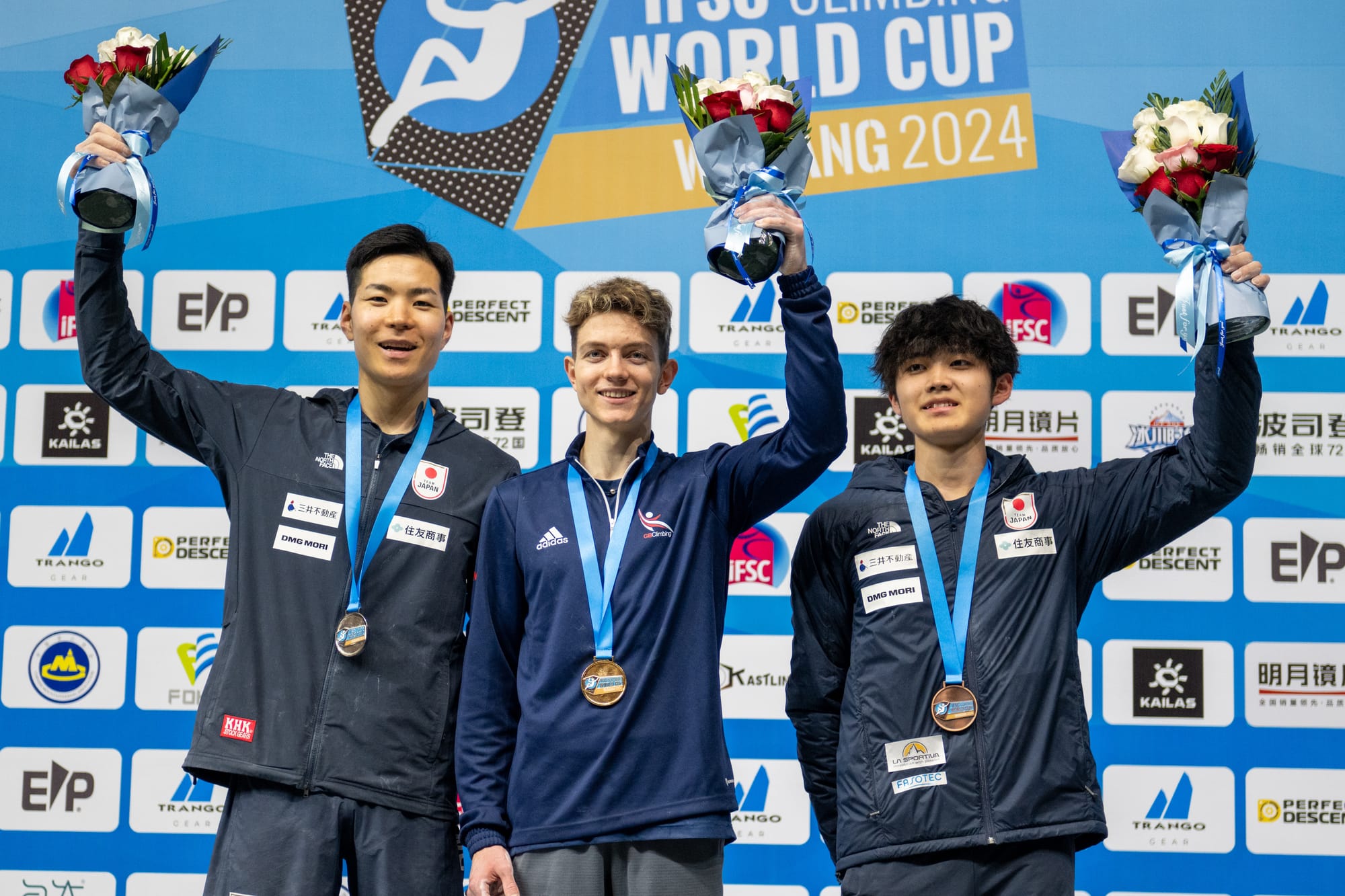 Men's podium: Toby Roberts, Taisei Homma and Sorato Anraku holding up their flowers 