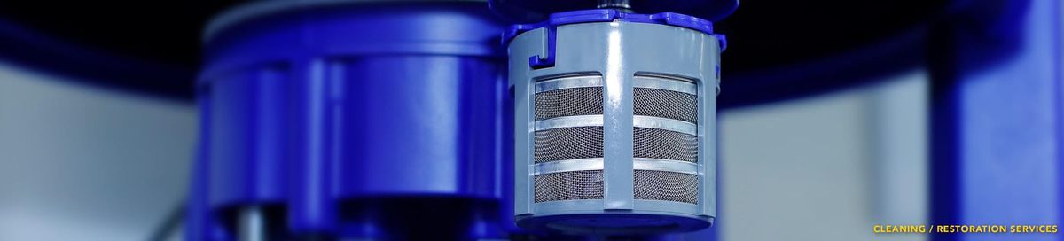 Photo of a grey basket with steel mesh siding attached to a blue machine, used for holding watch parts