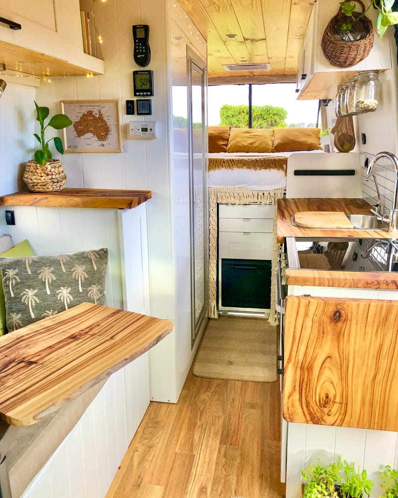 Interior of a campervan with kitchenette, seating and bed