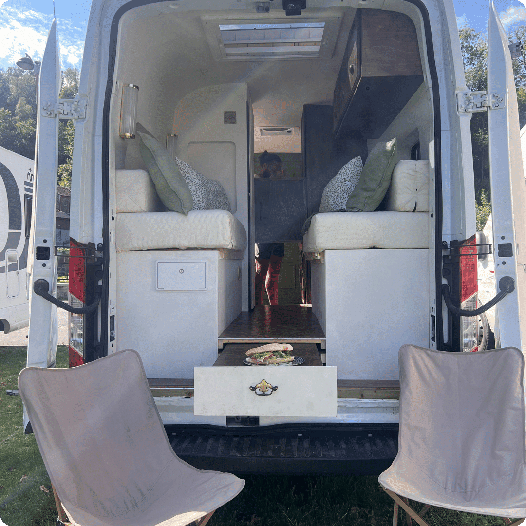 Campervan with camping chairs outside the open back doors