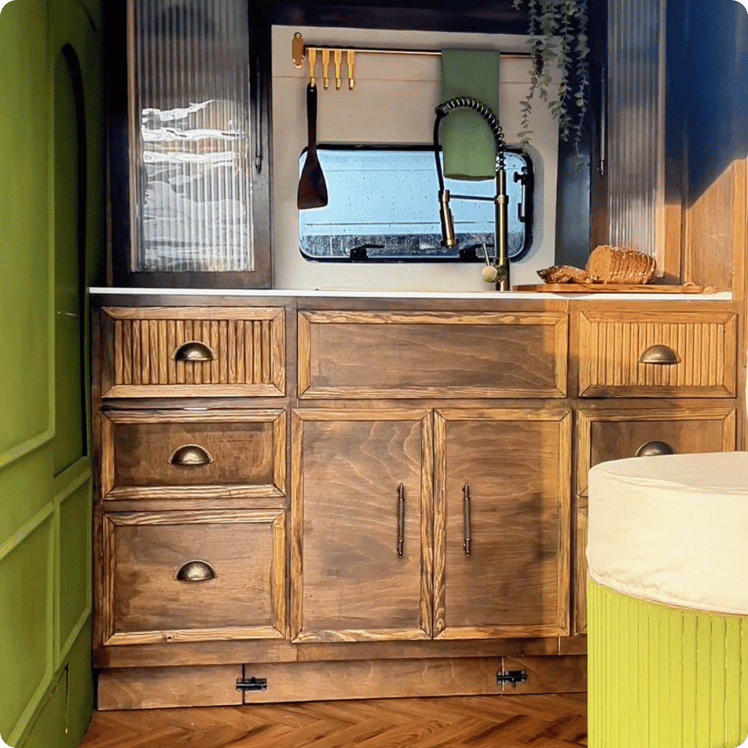 Wooden cabinets and sink in the back of a campervan
