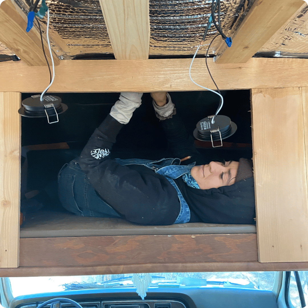 Woman on her back installing campervan electrics