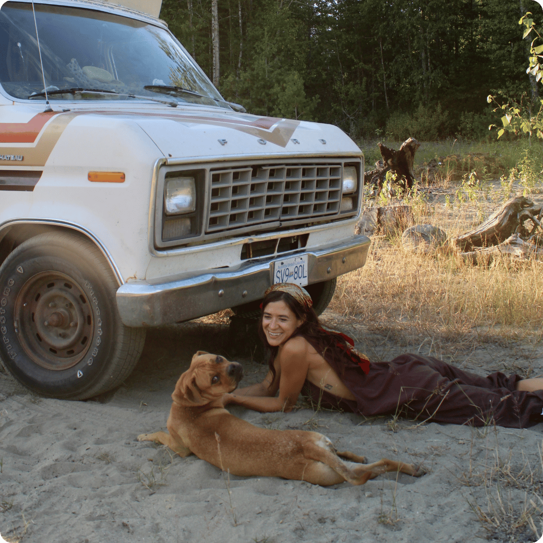 Woman and dog lying in the dirt beside a campervan