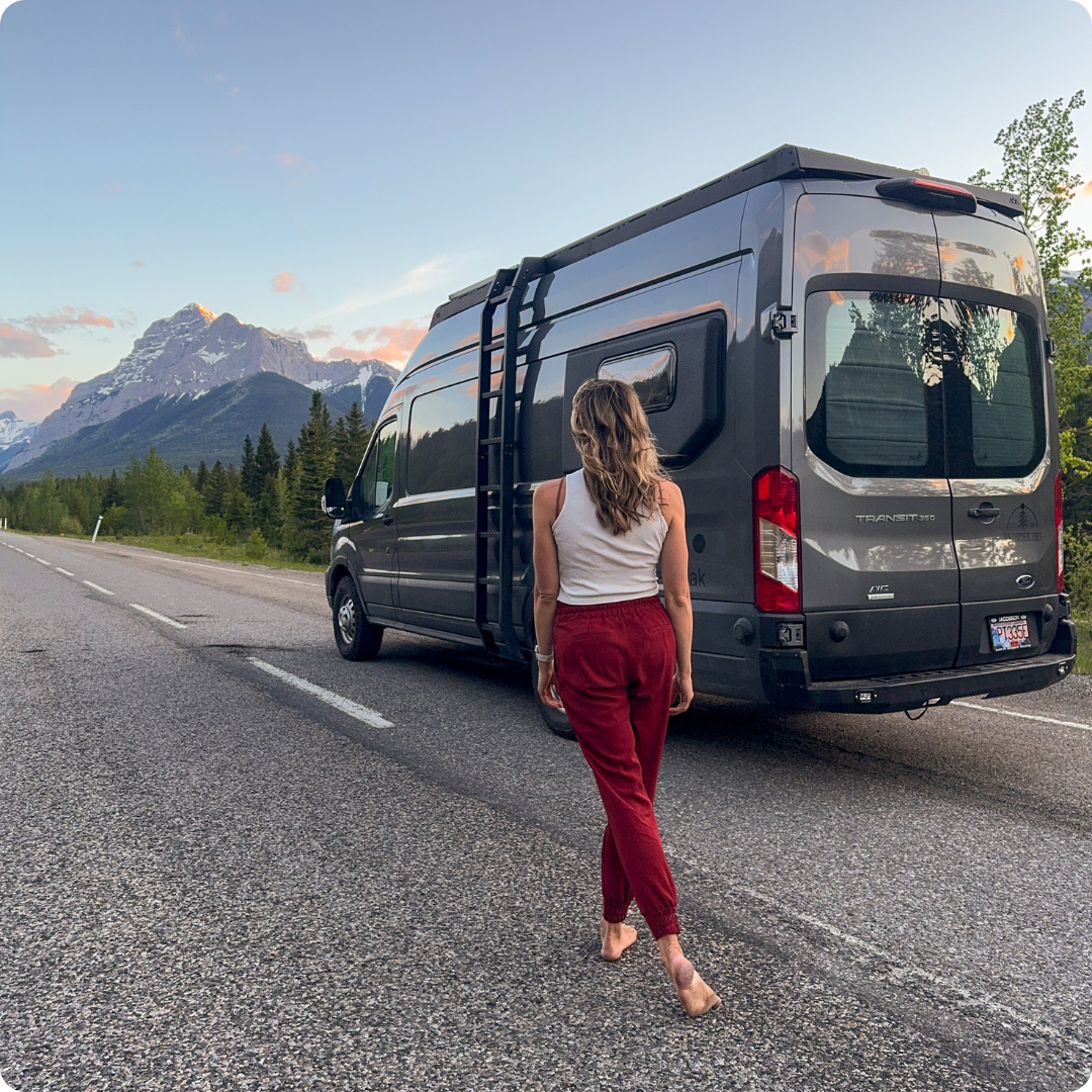 Girl standing next to campervan on an empty road