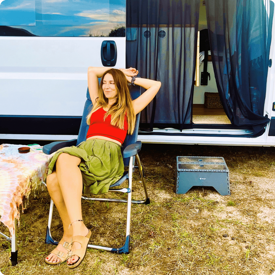 Girl sitting on a deck chair outside a converted van