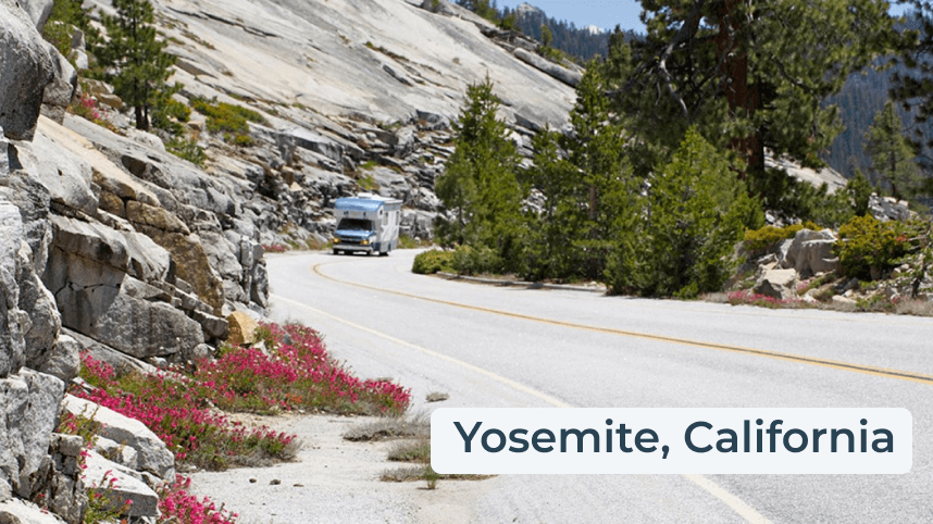 Campervan driving on a road with large rock face above