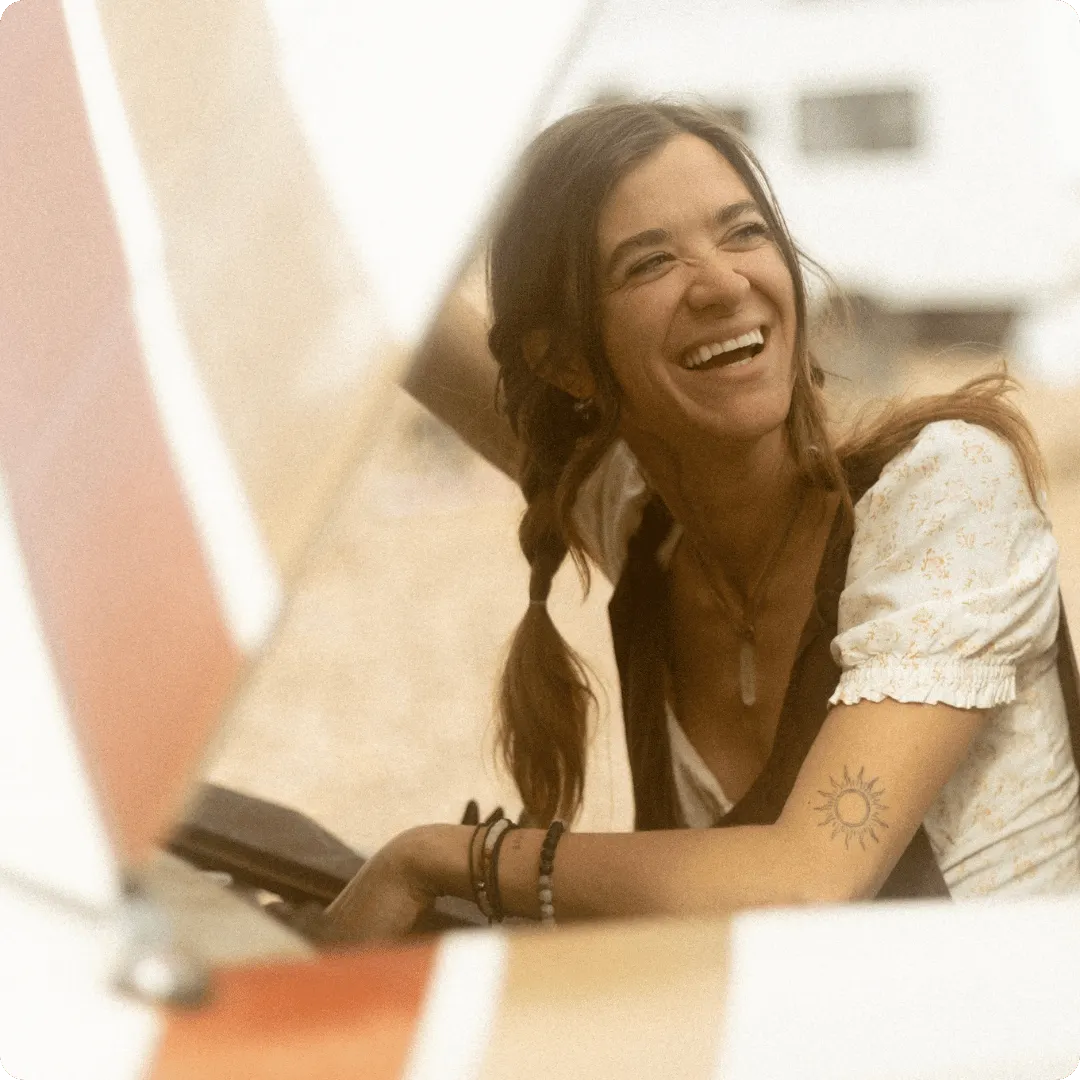 Woman smiling from under the hood of a campervan