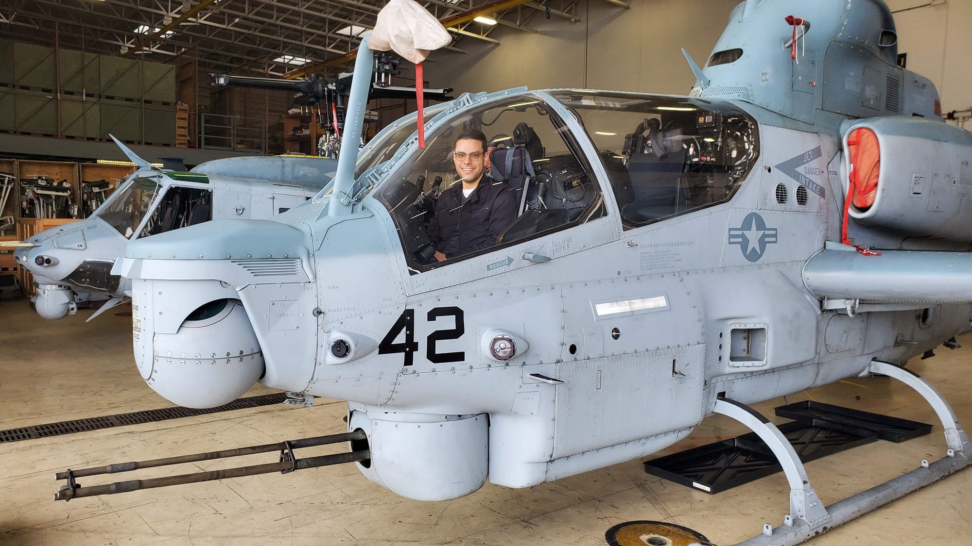 AH-1Z Viper helicopter inside a hanger with Mark sitting in the cockpit