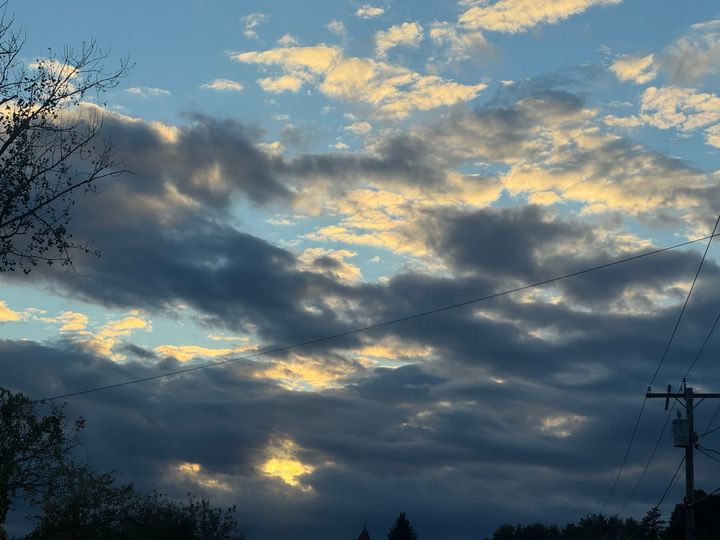 Clouds part at sunset, revealing soft bands of light through darkened sky—a reminder that even in darkness, the light is still present.
