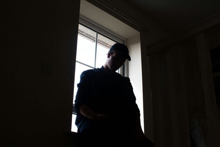 Person sitting in silhouette by a window, with light behind them.