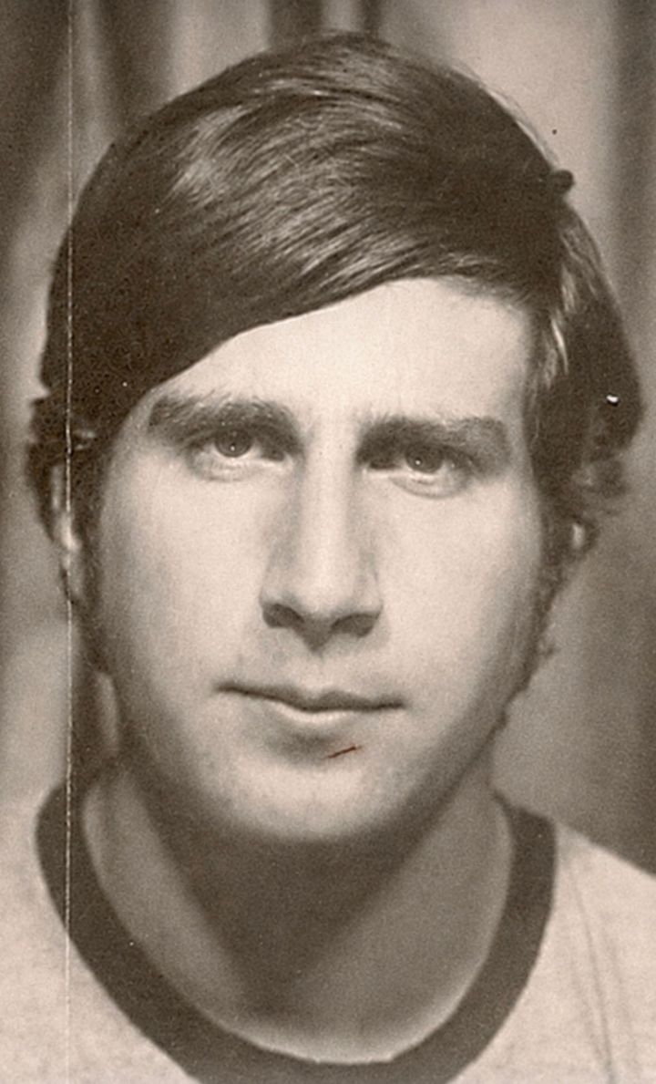 The author, younger here, looks into the camera with a small shaving cut beneath his lower lip, pausing to take in what he sees.