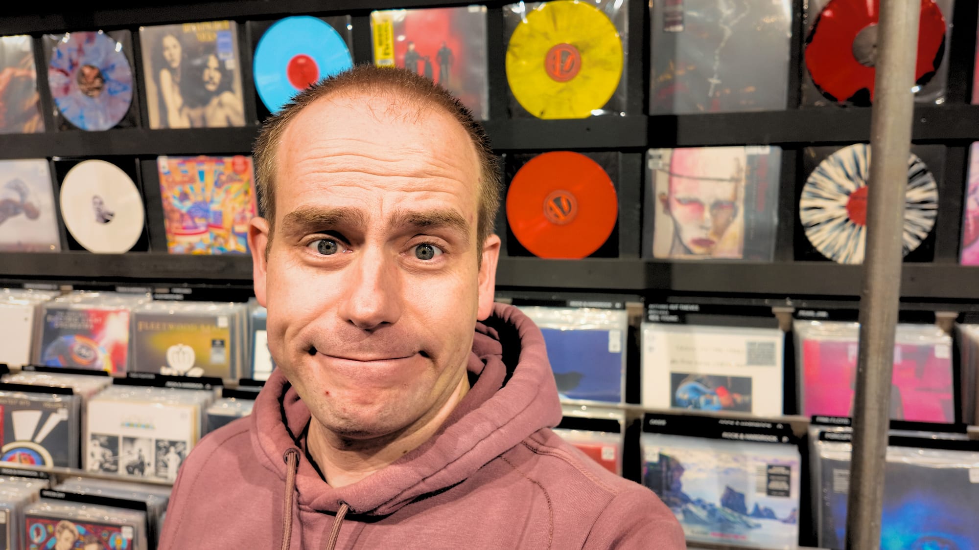 Frenck standing in front of a rack of Vinyl records at the record store