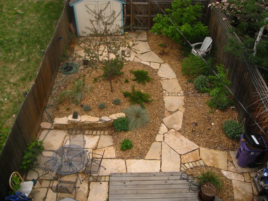 Overhead view of a backyard xeriscape with flagstone paths connecting patio rooms through mulched beds