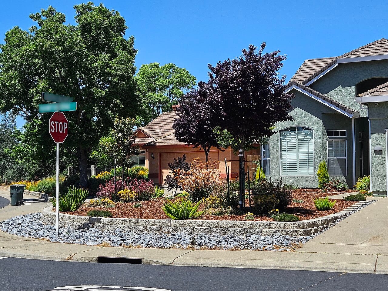 Residential xeriscape with hydrozoned planting beds under wood mulch and a rock border
