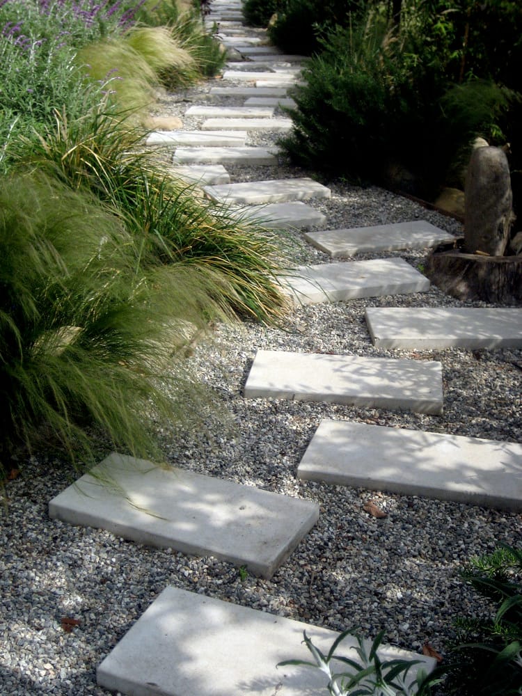 Paver path through gravel with dense ornamental grasses and lavender spilling over the edges