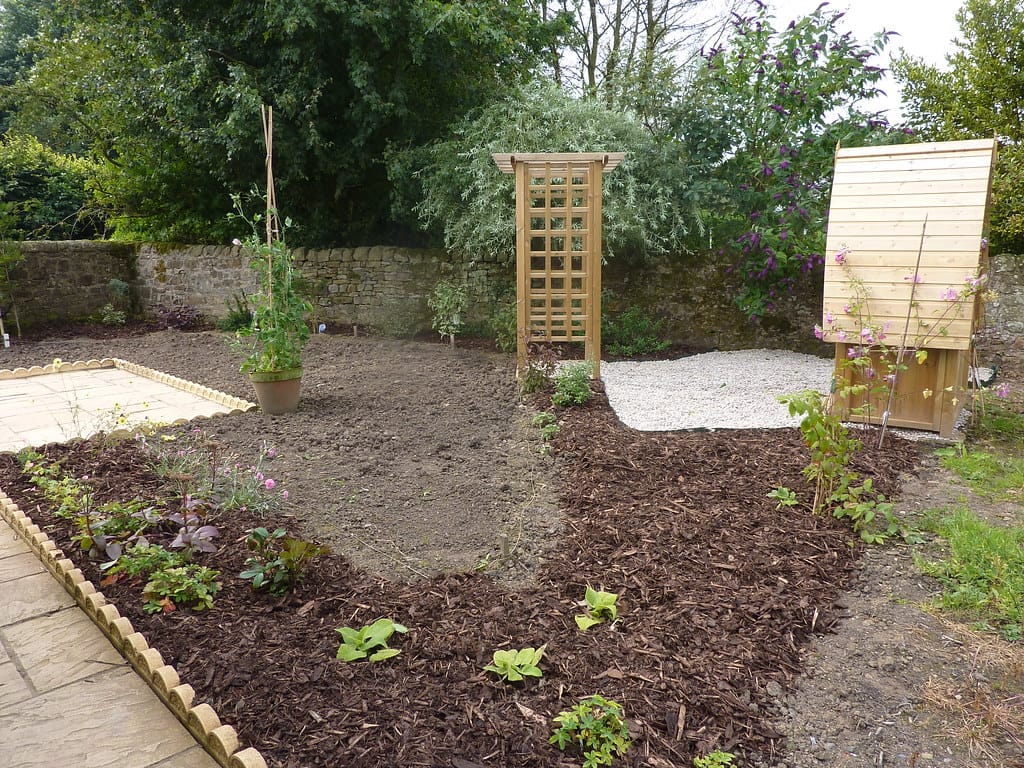 Garden with wood chip mulched planting beds and a pea gravel area beyond