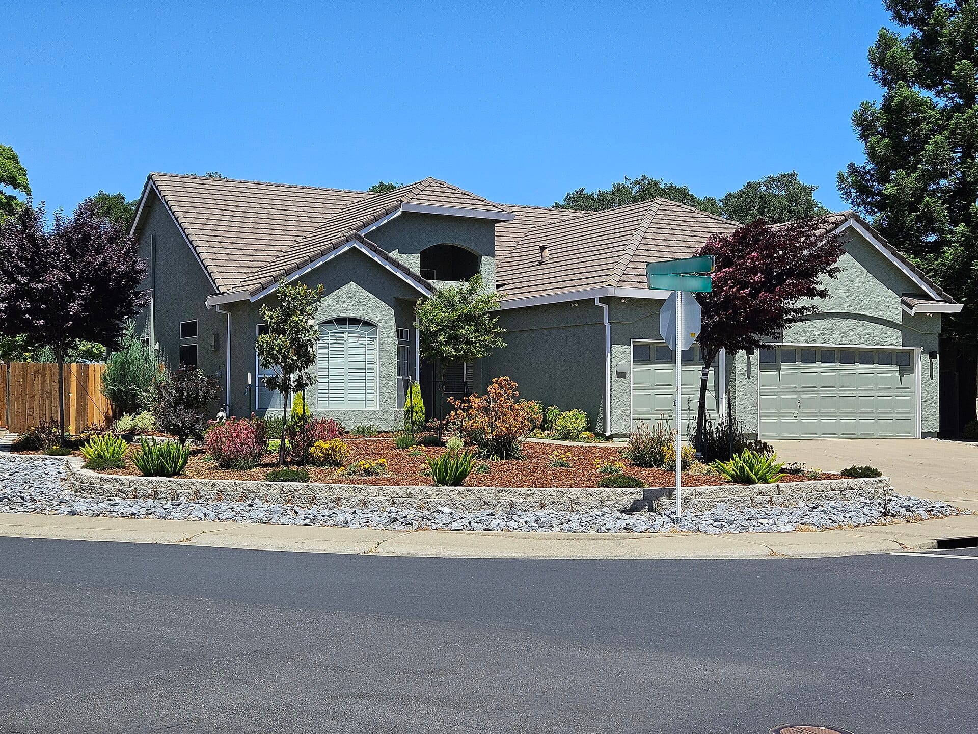 Suburban home with front lawn replaced by rock mulch, shrubs, and drought-tolerant plantings