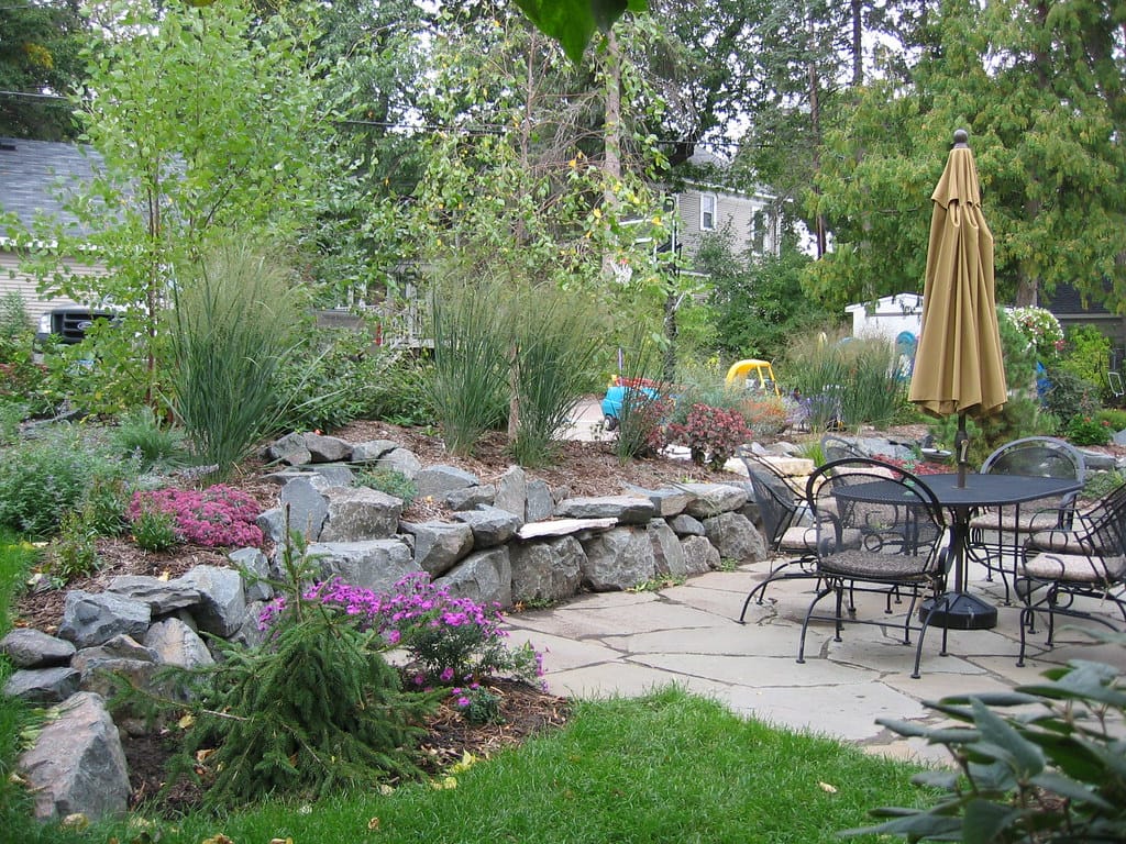 Flagstone patio with boulder retaining wall and planted beds, the most expensive xeriscape line item